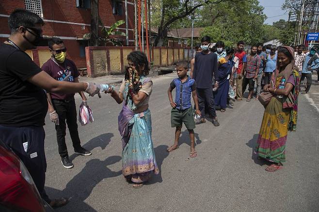 [가우하티=AP/뉴시스]신종 코로나바이러스 감염증(코로나19) 확산을 막기 위해 인도 전국이 봉쇄된 가운데 19일(현지시간) 인도 가우하티에서 주민들이 노숙자들에게 물과 음식을 나눠주고 있다. 2020.04.20.