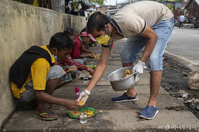 [가우하티=AP/뉴시스]신종 코로나바이러스 감염증(코로나19) 확산을 막기 위해 인도 전국이 봉쇄된 가운데 19일(현지시간) 인도 가우하티에서 한 남성이 도로의 노숙자들에게 음식을 나눠주고 있다. 2020.04.20.