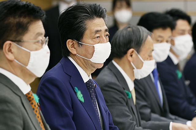 아베 신조 일본 총리(왼쪽 두 번째)가 16일 도쿄의 총리관저에서 열린 신종 코로나바이러스 감염증(코로나19) 대책본부 회의에서 마스크를 쓴 채 발언하고 있다. 코로나 예방을 위해 일본 정부가 전 가구에 배포하고 있는 마스크를 직접 쓴 것이다. /AP=연합뉴스