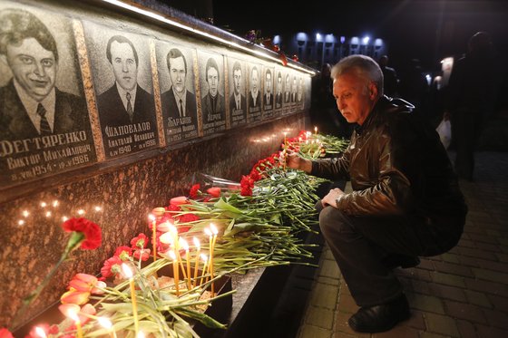 지난해 4월 26일 체르노빌 사고 33주기 추모 행사에서 사망자들의 비석 앞에 꽃을 놓는 시민. AP=연합뉴스