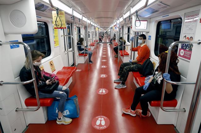 코로나19 최대 피해국 중 하나인 이탈리아가 4일부터 봉쇄 조치를 단계적으로 완화한 가운데 8일 밀라노의 지하철에서 마스크를 쓴 승객들이 최소한의 거리를 두고 앉아 있다. 바닥에도 최소한의 거리를 두기 위한 스티커가 붙어 있다.  밀라노=EPA 연합뉴스