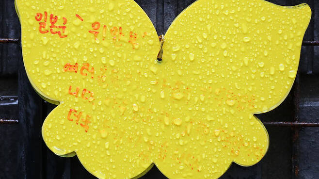19일 오전 서울 마포구 전쟁과여성인권박물관 외벽에 반쯤 메시지가 지워진 나비모양 메모에 빗물이 맺혀 있다.