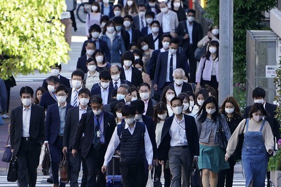 일본 정부가 긴급사태선언 한달 연장을 결정한 다음날인 지난 7일 도쿄의 직장인들이 마스크를 쓴 채 출근하고 있다. [AP=연합뉴스]