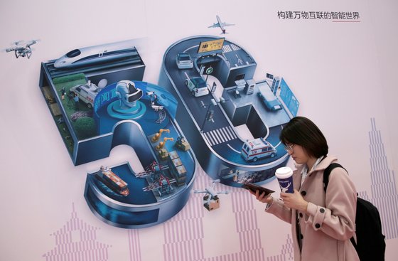 지난해 11월 중국 베이징에서 한 시민이 5G 광고 표지 옆을 걸어가고 있다.[로이터=연합뉴스]