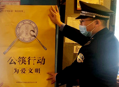 중국 경찰이 ‘공용 젓가락 운동’ 포스터를 벽에 붙이고 있다. 국가질량신문망