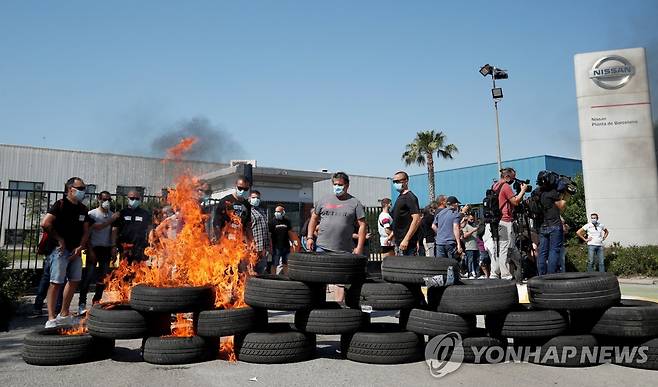28일 일본 닛산자동차의 스페인 바르셀로나 공장 직원들이 공장 폐쇄 결정에 항의하며 타이어에 불을 지른 채 시위를 하고 있다. [로이터=연합뉴스]
