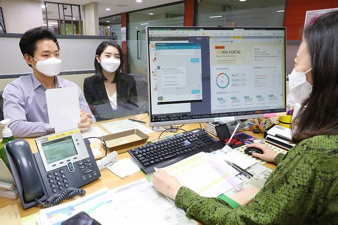 KB국민은행 여의도영업부 직원이 고객과 상담 중에 대출 서류, 급여이체 등록 여부를 RPA(Robotic Process Automation·로봇 처리 자동화) 포털과 RPA 챗봇으로 확인하는 모습./사진제공=KB국민은행