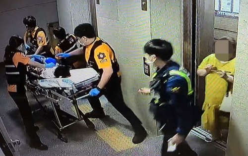 지난 1일 저녁 A군이 병원으로 옮겨지는 모습. 오른쪽 노란 옷이 계모 B씨. [연합뉴스TV 캡처]