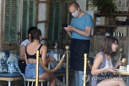 미국 캘리포니아 로스앤젤레스의 한 식당에서 웨이터가 마스크를 쓴 채 손님 주문을 받고 있다. [로이터=연합뉴스 자료사진]