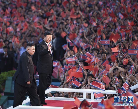 지난해 6월 20일 방북한 시진핑 중국 국가주석이 김정은 북한 국무위원장과 함께 평양 5.1 경기장에 운집한 10만 북한 관중을 향해 손을 흔들어 인사하고 있다. [중국 신화망]