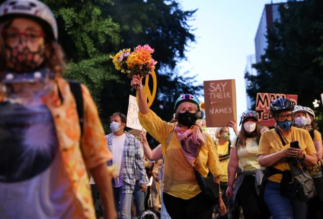 포틀랜드에서 22일 노란 셔츠를 입은 엄마들이 인종차별 및 경찰 폭력 반대 시위를 하고 있다. 포틀랜드=로이터 연합뉴스