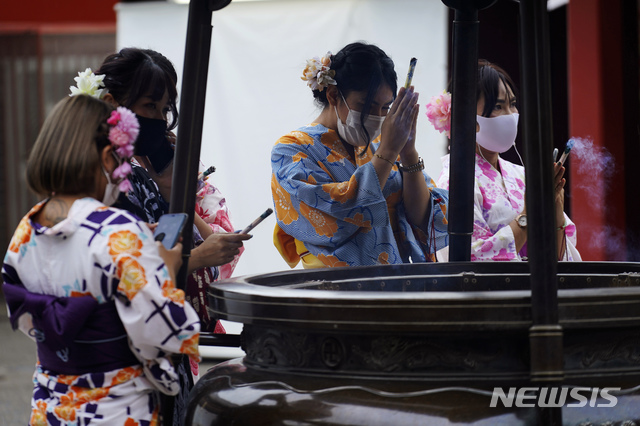 [도쿄=AP/뉴시스]27일 일본 전통 기모노를 입은 한 식당 직원들이 마스크를 쓰고 도쿄 아사쿠사 지구에서 향을 피우며 기도하고 있다. 도쿄 당국은 27일 131명의 신종 코로나바이러스 감염증(코로나19) 확진자가 확인됐다고 밝혔다. 2020.07.27.