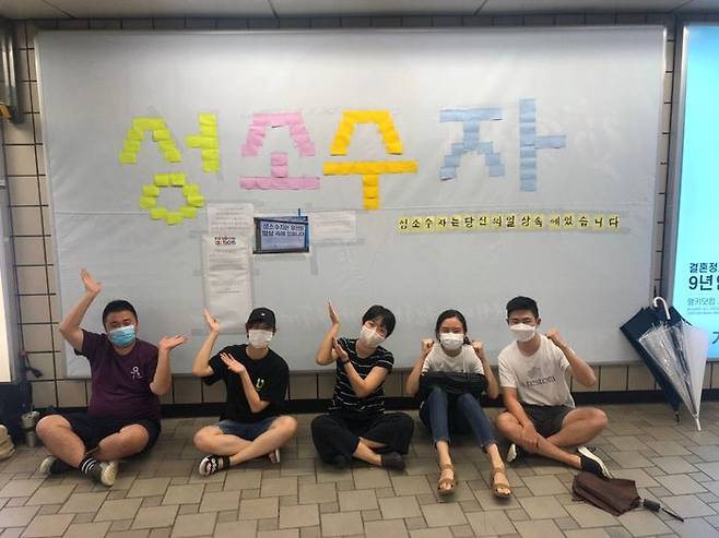 '성소수자차별반대 무지개행동' 관계자들이 광고판이 철거된 자리에 메모지를 붙여 '성소수자'라는 문구를 만들고 기념사진을 찍는 모습