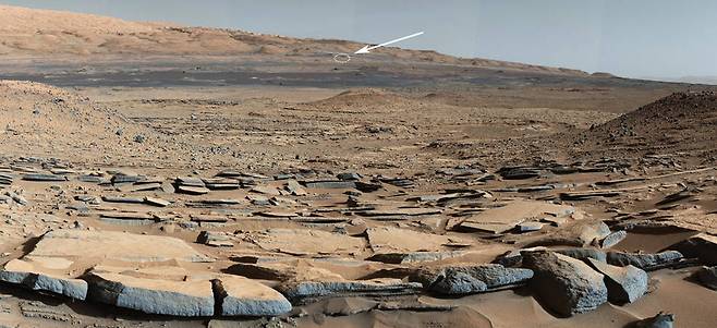 지난 2014년 3월 24일 큐리오시티가 촬영한 화성 표면의 전경이다. 저멀리 화살표가 가르키는 원이 2020년 7월 30일 기준 큐리오시티가 현재 있는 위치로 대략 5㎞ 정도 떨어져있다.