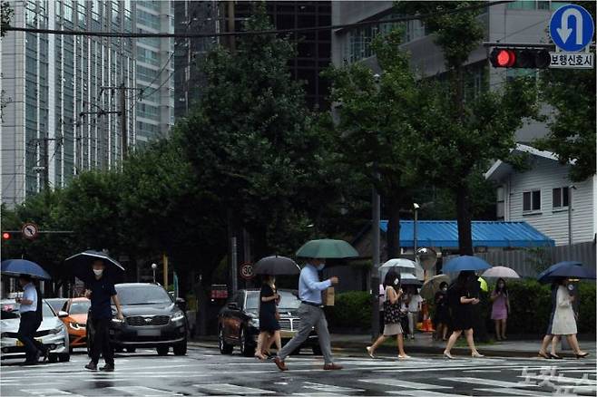 서울·인천·경기 등 수도권에 호우경보가 내려진 3일 오후 정부서울청사 부근 횡단보도에서 시민들이 우산을 쓴 채 길을 건너고 있다. 황진환기자