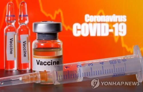 신종 코로나바이러스 감염증(코로나19)이라는 글씨 앞에 놓인 백신 약품. [로이터=연합뉴스 자료사진]