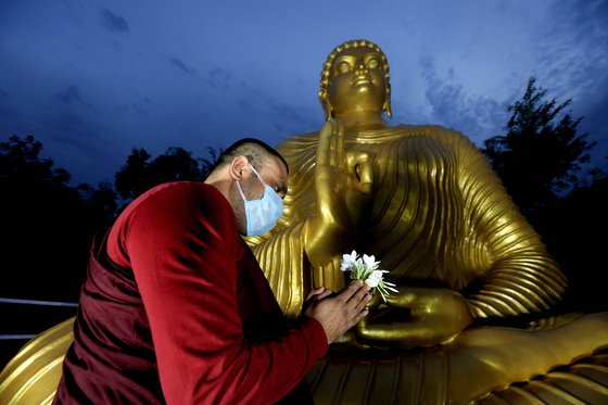 카스트 제도에서 고통받은 불가촉천민들이 최근 힌두교에서 불교로 개종하는 사례가 늘고 있다. 인도 보팔에서 불교 승려가 마스크를 쓴 채 부처님 상 앞에 꽃을 들고 기도를 올리고 있다. [EPA=연합뉴스]