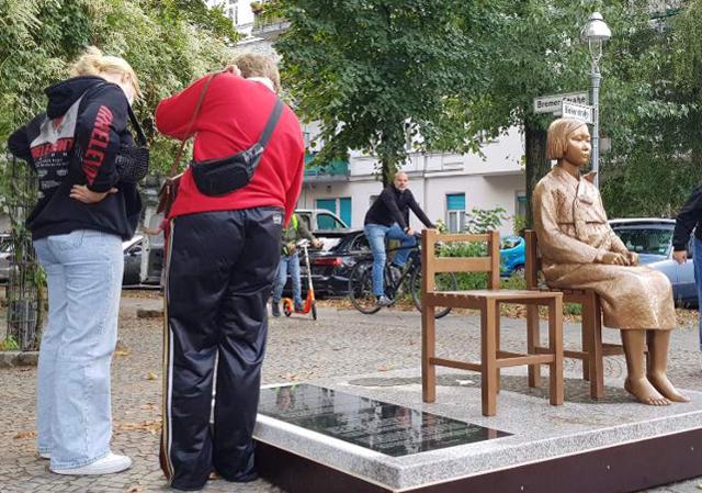 독일 수도 베를린에 설치된 '평화의 소녀상'에 쓰인 비문을 25일(현지시간) 지나가던 시민들이 읽고 있다. 베를린=연합뉴스