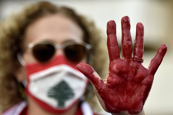 레바논 베이루트에서 20일(현지시간) 한 반정부 시위대가 붉은색 페인트를 피처럼 보이게 칠한 손을 들어 보이며 시위를 벌이고 있다. 시위대는 정부를 규탄하며 새로운 총선을 요구하고 있다. EPA=연합뉴스