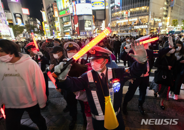 [도쿄=AP/뉴시스]10월 31일 저녁 일본 도쿄의 시부야 거리의 한 교차로에서 경찰관들이 몰려든 핼러윈 인파로 분주하게 교통정리를 하고 있다. 이날 시부야 거리에 핼러윈을 즐기려는 수천 명이 몰려들었으며 시 당국은 코로나19 확산 우려로 사람들에게 모이지 말 것을 요청했다. 2020.11.01.
