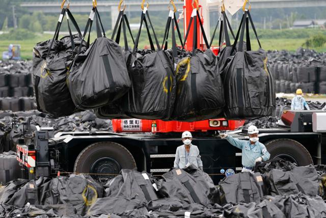 2013년 후쿠시마 발전소 인근서 관계자들이 방사능 오염물질을 운반하고 있다. 후쿠시마=로이터 연합뉴스