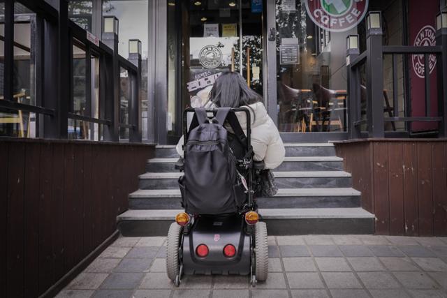 지난 2일 서울 종로구 구도심 일대의 한 점포 앞 계단에 장애인 에디터 문화진(33)씨의 전동휠체어가 서 있다. 이날 둘러본 60여 개 점포 대다수가 입구에 높은 턱이나 계단이 설치돼 있어 휠체어의 진입이 불가능했다.