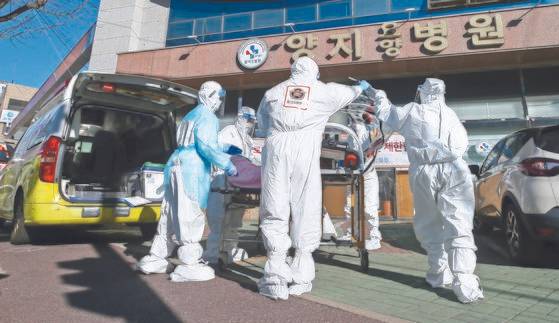 지난 17일 오후 울산시 남구 양지요양병원 앞에서 의료진과 119구급대원들이 신종 코로나바이러스 감염증(코로나19) 확진 환자를 구급차로 옮기고 있다. 연합뉴스