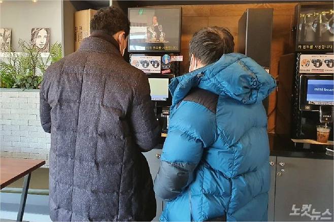 두 중년 남성이 강릉시 구정면의 한 무인 카페에서 기계를 작동해 직접 커피를 뽑고 있다. (사진=유선희 기자)