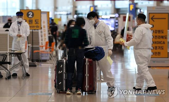 인천공항 방역강화 (영종도=연합뉴스) 김인철 기자 = 신종 코로나바이러스 감염증(코로나19) 확산세가 계속되는 지난 27일 인천국제공항 제1터미널 입국장에서 방역 관계자들이 입국자들에게 동선을 안내하고 있는 모습. yatoya@yna.co.kr