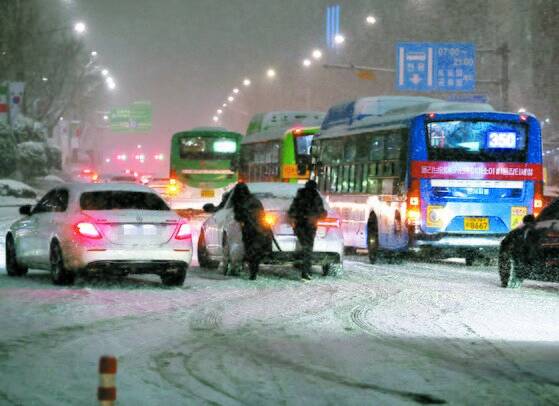 서울 전역에 대설주의보가 발효된 6일 오후 서울 삼성역 인근 도로에서 시민들이 차를 밀고 있다.연합뉴스