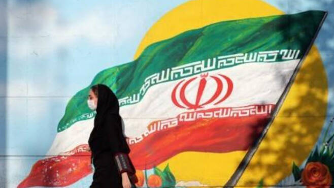 이란 국기 앞을 지나는 테헤란 시민. 연합뉴스