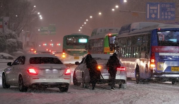 폭설이 내린 지난 6일 저녁, 서울 삼성역 인근 도로에 시민들이 미끄러진 차를 밀고 있다./연합뉴스