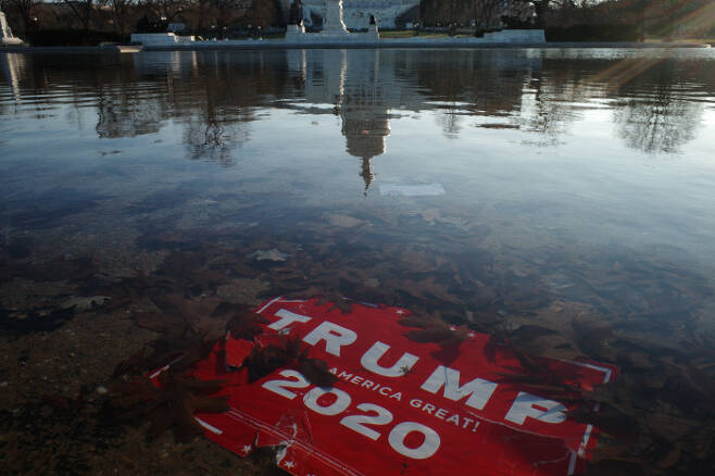 한바탕 폭풍이 휩쓸고 간 뒤 ‘트럼프 2020’이라고 적힌 플래카드가 7일(현지시간) 미국 워싱턴 연방의회 의사당 앞 연못에 잠겨 있다. 워싱턴 | EPA연합뉴스