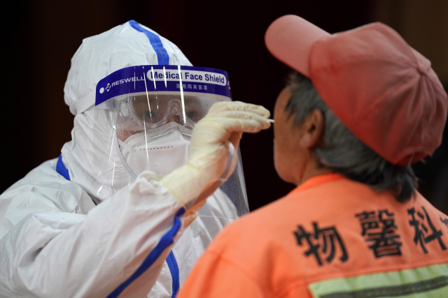중국 수도 베이징 순이(順義)구에 마련된 한 검사소의 의료인이 핵산검사를 위해 주민의 검체를 채취하고 있다./연합뉴스