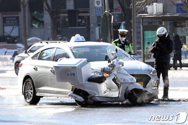 서울 광화문 사거리에서 지난 7일 교통사고가 발생해 배달 노동자가 사고를 처리하고 있다.2021.1.7/뉴스1 © News1 황기선 기자