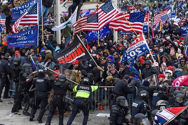 1월6일(현지시각) 미국 워싱턴의 의사당 앞에서 트럼프 대통령 지지자들과 경찰이 충돌하고 있다. 트럼프 지지자들은 조 바이든 대통령 당선자의 승리를 인정하지 않고 의사당을 점거했다. 워싱턴/AFP 연합뉴스