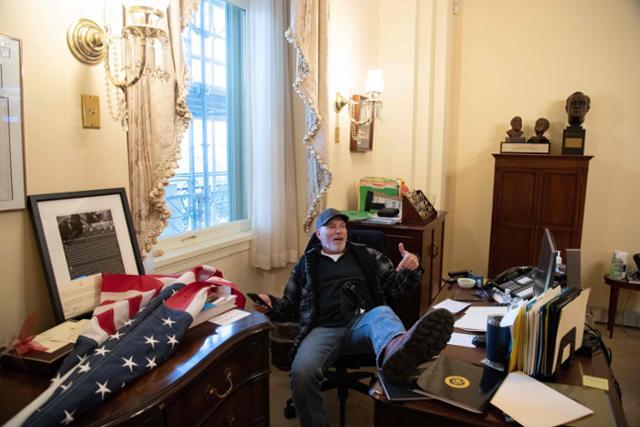 미국 국회의사당에 난입한 도널드 트럼프 대통령 지지 시위대 한 명이 6일(현지시간) 낸시 펠로시 하원의장 사무실까지 들어와 의자에 앉아 발을 책상 위에 올리고 있다. 워싱턴=AFP 연합뉴스