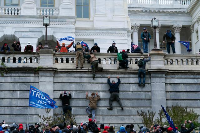도널드 트럼프 미국 대통령 지지 시위대가 6일 워싱턴 연방의회 의사당 서쪽 벽을 기어오르고 있다. 워싱턴=AP 연합뉴스