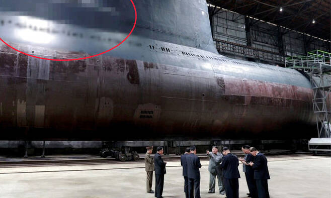 김정은 북한 국무위원장(가운데)이 2019년 7월 새로 건조한 잠수함을 시찰하고 있다. 잠수함발사탄도미사일(SLBM) 발사관으로 추정되는 부분(붉은원)과 잠망경 등 감시장비가 장착됐을 것으로 보이는 부분(푸른원)이 모자이크로 처리돼 있다. 세계일보 자료사진