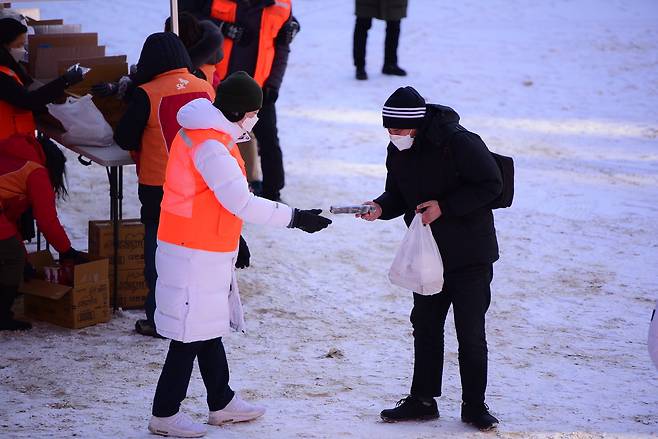 지난 8일 명동밥집이 마련된 옛 계성여중고 운동장에서 관계자가 노숙인에게 도시락 나눔을 하고 있다.(천주교 서울대교구 제공)© 뉴스1