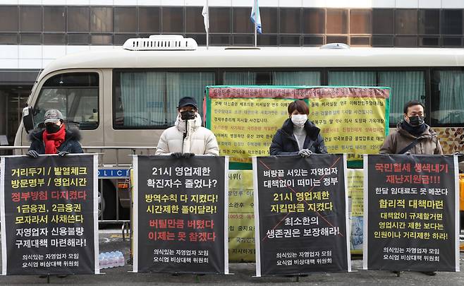 Members of a coalition for the rights of restaurant businesses stage a protest Tuesday near the headquarters of the ruling Democratic Party of Korea in Yeouido, western Seoul, to demand the government remove the 9 p.m. operations curfew under COVID-19 social distancing rules. (Yonhap)