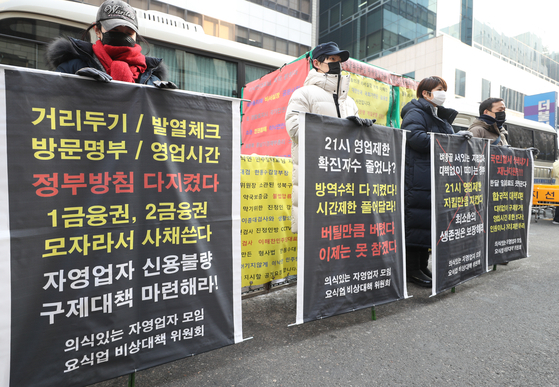Members of an emergency committee representing restaurant owners stage a protest in front of the ruling Democratic Party's headquarters in Yeouido, western Seoul, on Tuesday, urging them to lift the regulation that forces restaurants to close at 9 p.m. [YONHAP]