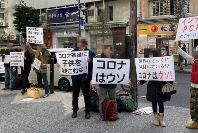 지난 16일 일본 도쿄 도심에서 ‘코로나는 거짓’ 등의 글이 적힌 손 팻말을 들고 시위를 벌이고 있다. 사진=소셜미디어(SNS)캡처