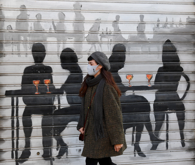 11일 이탈리아 밀라노의 나발리오 그란데에 있는 폐쇄된 식당 앞에서 얼굴 마스크를 쓴 소녀가 걷고있다. /EPA연합뉴스