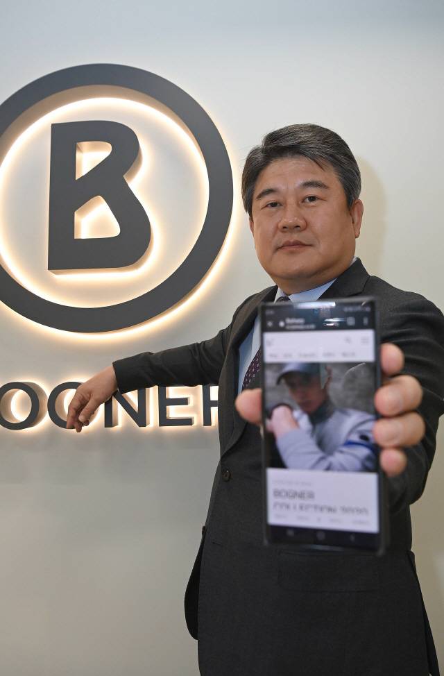 하현 ㈜국보 대표이사가 골프웨어 브랜드 보그너 로고를 배경으로 포즈를 취하며 곧 서비스를 시작할 온라인 쇼핑몰 화면을 보여주고 있다. /이호재기자