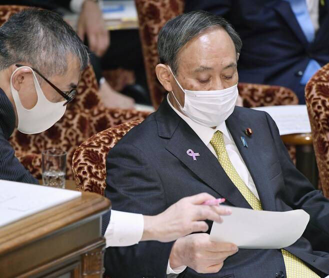 (도쿄 교도=연합뉴스) 스가 요시히데(菅義偉) 일본 총리가 작년 1월 25일 오후 일본 참의원 예산위원회에서 질문에 답변하기 위해 관계자로부터 자료를 받고 있다. 스가 총리는 원고에 지나치게 의존해 자기 목소리가 없다는 평가를 받았다.