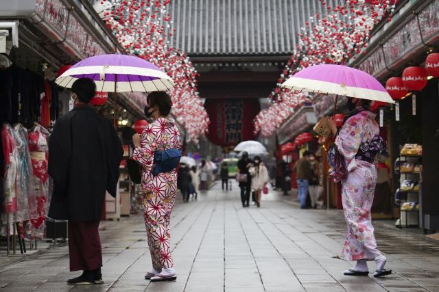 일본 도쿄 아사쿠사의 지역의 쇼핑 거리에서 12일 전통 복장을 한 사람들이 마스크를 쓰고 걷고 있다. /AP연합뉴스