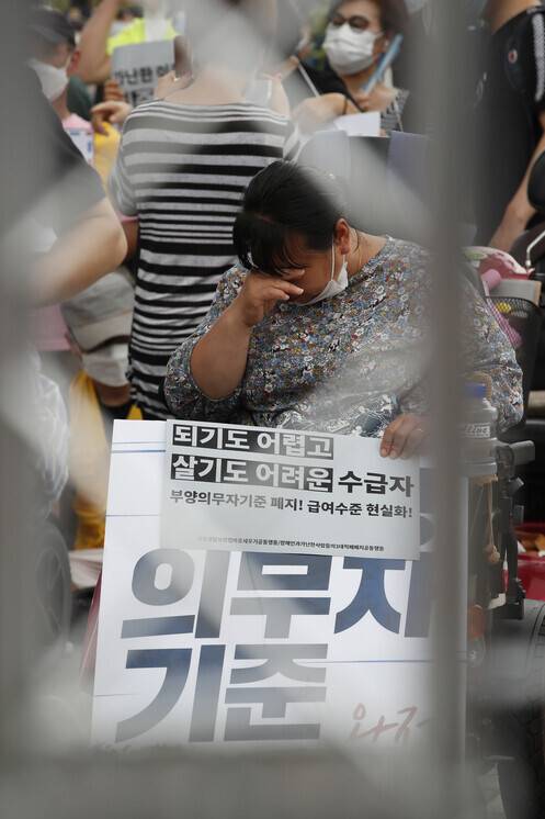 제60차 중앙생활보장위원회가 열린 지난해 7월31일 오후 정부서울청사 앞에서 `장애인과 가난한 사람들의 민중생활보장위원회 기자회견'이 열려 참가자들이 정부에 의료급여 항목 등을 포함한 부양의무자 기준 완전히 폐지 등을 촉구하는 구호를 외치다 이마에 흐르는 땀을 닦고 있다. 이정아 기자 leej@hani.co.kr