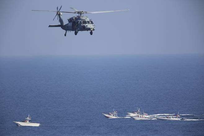 미 해군 헬리콥터가 지난달 호르무즈 해협에서 이란 혁명군 경비정이 순찰 중인 가운데 비행하고 있다.[AP]