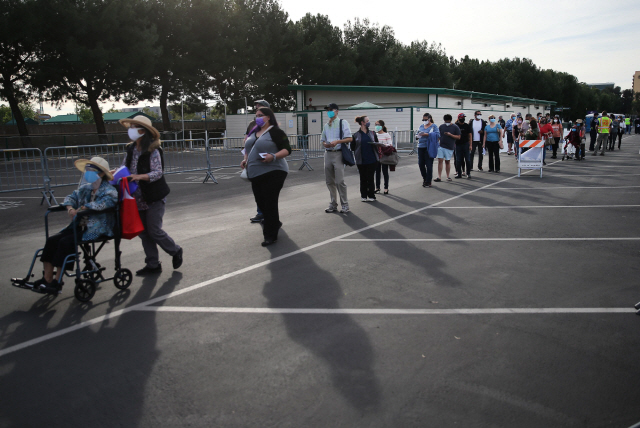 13일(현지 시간) 미국 캘리포니아주 애너하임의 디즈니랜드 주차장에서 코로나19 백신 접종을 기다리는 사람들이 길게 줄을 서 있다./AFP연합뉴스